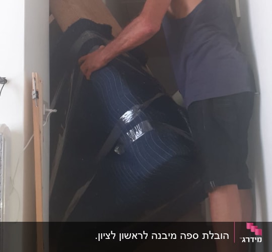 אדם עם מסכה מרים חפץ גדול עטוף בבד